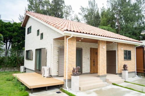 a small white brick house with a deck at Comfy Resort Villa Onna in Onna