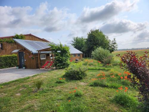 a cabin with a garden and a field of flowers at le chalet de la ferme du tertre in Villers-au-Tertre