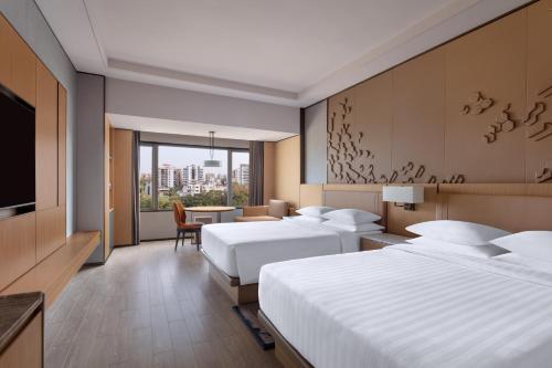 a hotel room with two beds and a television at Surat Marriott Hotel in Surat