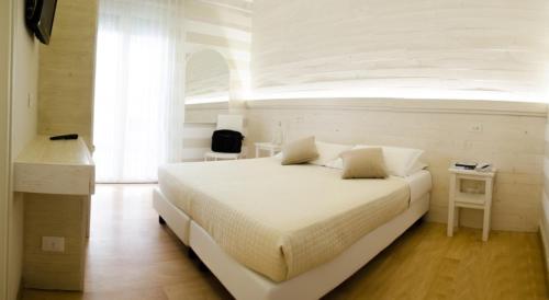 1 dormitorio con 1 cama blanca grande y escritorio en Mona Lisa Hotel, en Cattolica