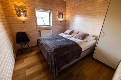 a small bedroom with a bed in a wooden wall at Efsti-Dalur Cottages in Úthlid