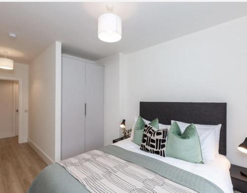 a bedroom with a bed with green and white pillows at Deluxe Seaview Apartment in Dun Laoghaire