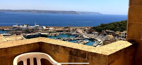 a white chair sitting on top of a building with a harbor at B&b Seaview terrace in Għajnsielem