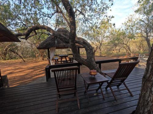 a table and chairs on a wooden deck with a tree at South Safari Lodge in Marloth Park