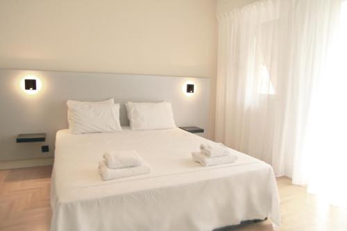 um quarto com uma cama branca e toalhas em Citybreak Apartments 301 em Atenas