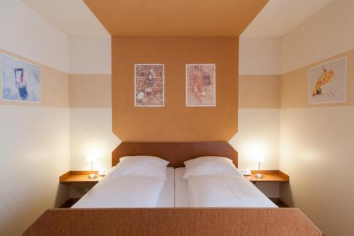 a bedroom with a bed with two pillows and two lamps at Hotel Garni Haus zum Gutenberg in Hallbergmoos