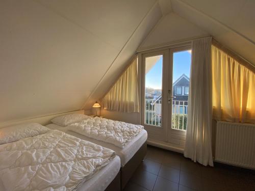 Un dormitorio con dos camas y una gran ventana. en Previnaireweg 24, en Callantsoog