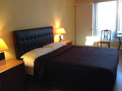 a bedroom with a bed and two lamps and a window at Motel Rive Du Lac in Saint-Zotique