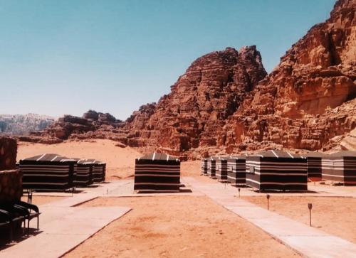 um grupo de bancos no deserto com montanhas em Wadi rum Rozana camp em Wadi Rum