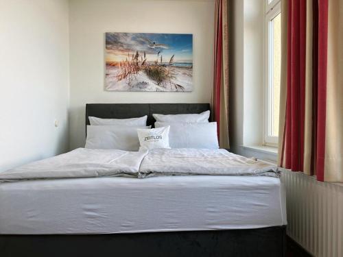 a bedroom with a bed with white sheets and a window at Zeitlos Hotel Garni in Scharbeutz