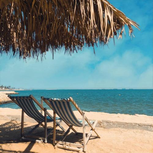 two chairs sitting under an umbrella on the beach at Fanara Apartments Armed Forces in Fayed