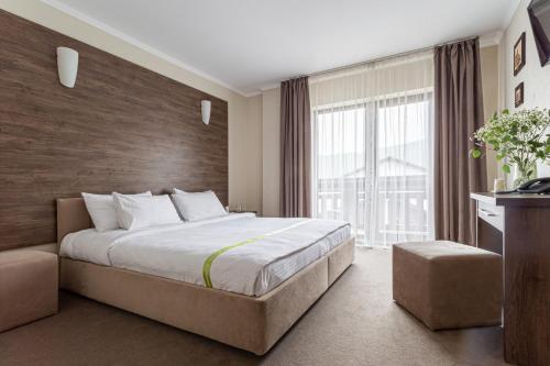 - une chambre avec un grand lit et une grande fenêtre dans l'établissement Graal resort, à Bukovel