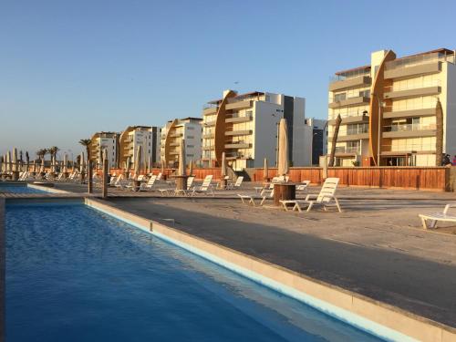 Una piscina con sillas y edificios al fondo. en Apartamento Frente a Islas Ballestas, en Paracas