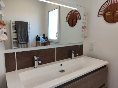 une salle de bain avec un lavabo blanc et un miroir dans l'établissement La tranquille escale, à Bretignolles-sur-Mer