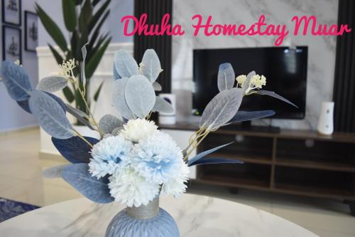 a blue vase with blue and white flowers on a table at Dhuha Homestay Muar in Muar