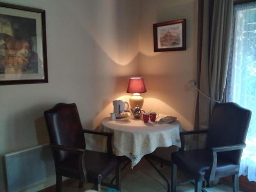 a small table with chairs and a lamp on it at La Chevallerie - Tranquil oasis in Isigny-le-Buat
