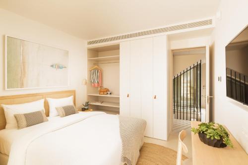 a white bedroom with a white bed and a window at Verdelago Resort in Praia Verde