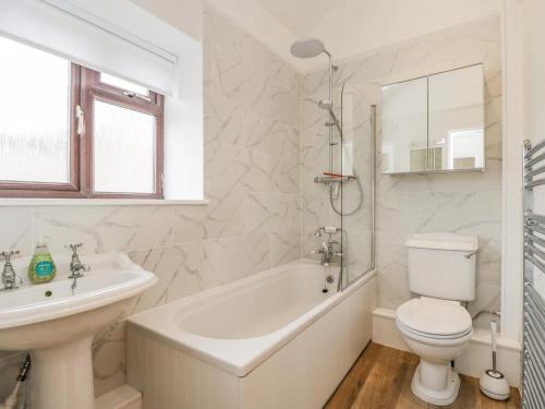 een witte badkamer met een bad, een toilet en een wastafel bij 2 Church Street in Chipping Norton