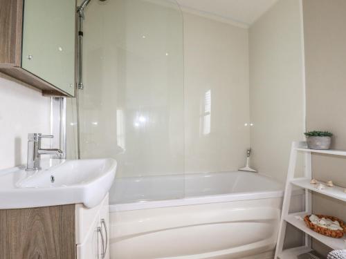 a white bathroom with a tub and a sink at No 4 Fistral in Newquay