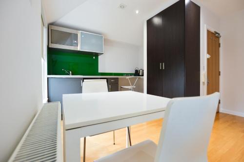 cocina con mesa blanca y sillas blancas en Concept Serviced Apartments by Concept Apartments, en Londres