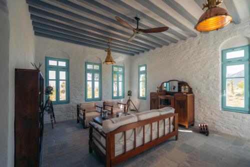 een woonkamer met banken en een plafondventilator bij Eco-Luxe Retreat in Ano Petali, Sifnos in Apollonia