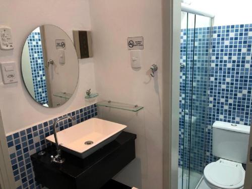 a bathroom with a sink and a mirror and a toilet at Hotel Natal in Santos
