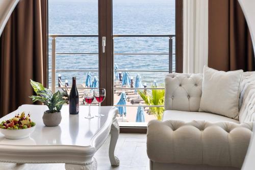 a living room with a white couch and a table with wine glasses at Elite Hotel Yalıkavak in Yalıkavak