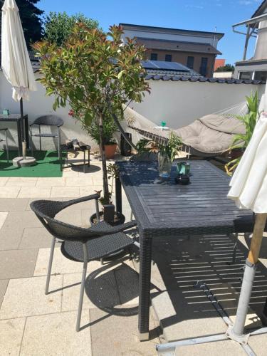 a table and chairs and a hammock on a patio at Gästehaus Tante Tienchen 7 Minuten zu Fuss zum Europa Park , plus kostenloses Parkplatzticket Rulantica ,alle unsere Suiten haben einen Balkon in Rust