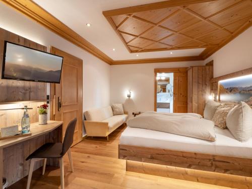 a bedroom with a bed and a desk and a tv at Hotel Garni Ferienhof in Mayrhofen