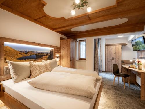 a bedroom with a large bed and a desk at Hotel Garni Ferienhof in Mayrhofen