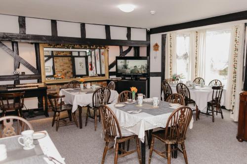 a dining room with tables and chairs and a piano at Sherwood Hotel in Margate