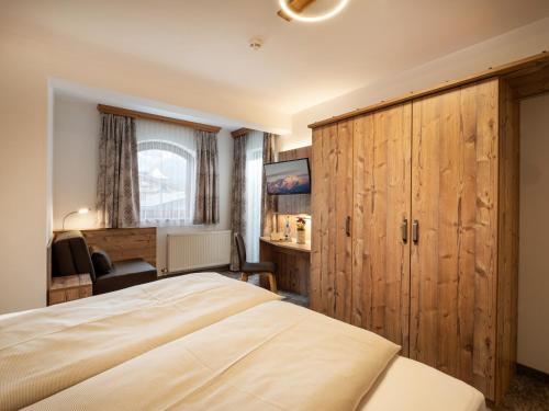 a bedroom with a large bed and a desk at Hotel Garni Ferienhof in Mayrhofen