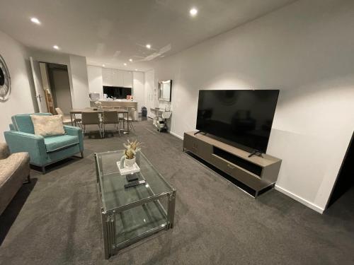 a living room with a television and a couch and a table at Fantastic 3 Bedroom Apartment in Southbank in Melbourne