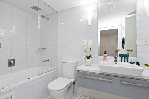 a white bathroom with a toilet and a sink at Lily - North Terrace Cityscape Residence in Adelaide