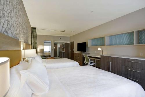 a hotel room with two beds and a desk at Home2 Suites By Hilton Dayton South in Miamisburg