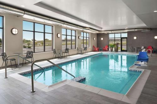 a pool in a hotel with chairs and tables at Home2 Suites By Hilton Madison Central Alliant Energy Center in Madison