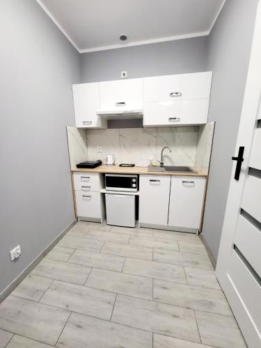 a kitchen with white cabinets and a tile floor at Mini Apartamenty Poznań in Poznań