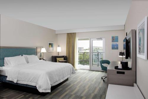 a hotel room with a bed and a balcony at Hampton Inn Dunedin, Fl in Dunedin