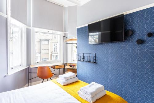 1 dormitorio con 1 cama y TV en la pared en Kensington Rooms - Philbeach Gardens, en Londres
