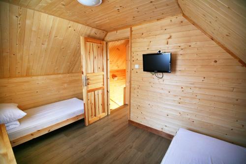 a wooden room with a tv and a bed at Domki ELDORADO in Dębki