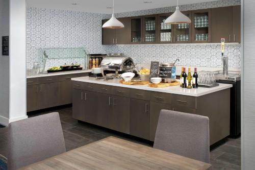 デンバーにあるHomewood Suites By Hilton Denver Airport Tower Roadの茶色のキャビネットとワインボトルが置かれたカウンターのあるキッチン