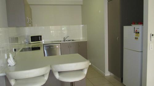a kitchen with a white counter and a refrigerator at Edge Apartments Cairns in Cairns