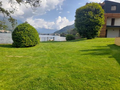 a yard with a lake and a house at d'Ocalée Holiday Experience lago d'Orta in Omegna