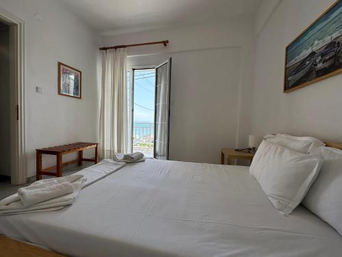 a large white bed in a room with a window at Anemomylos apartment sea view in Pefkohori