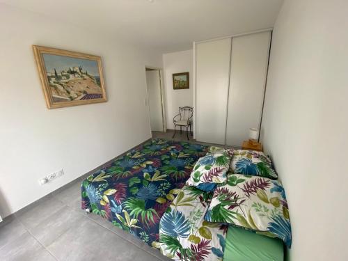 a bedroom with a bed with a colorful bedspread at APPARTEMENT TYPE 2 NEUF +GRANDE TERRASSE in Le Lavandou