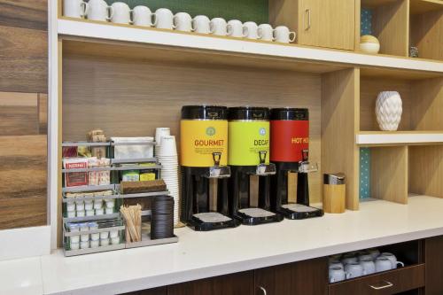 a row of coffee cups on a shelf in a kitchen at Home2 Suites By Hilton West Bloomfield, Mi in North Farmington