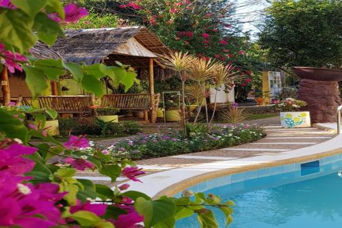 a garden with a swimming pool and flowers at Hanbee's Resort in Puerto Princesa City
