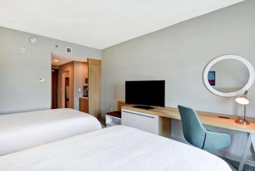 a hotel room with two beds and a desk with a television at Hilton Garden Inn Biloxi in Biloxi