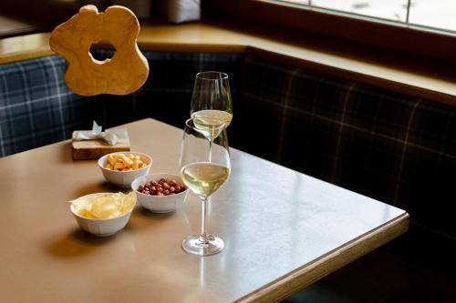 a table with two glasses of white wine and snacks at Suàn Hotel in Ziano di Fiemme