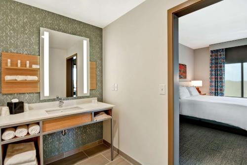 a bathroom with a sink and a bed and a mirror at Hilton Garden Inn Biloxi in Biloxi